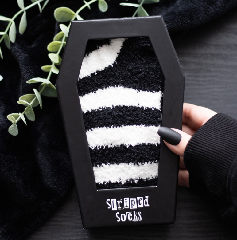 Fluffy black and white striped socks in a coffin-shaped gift box