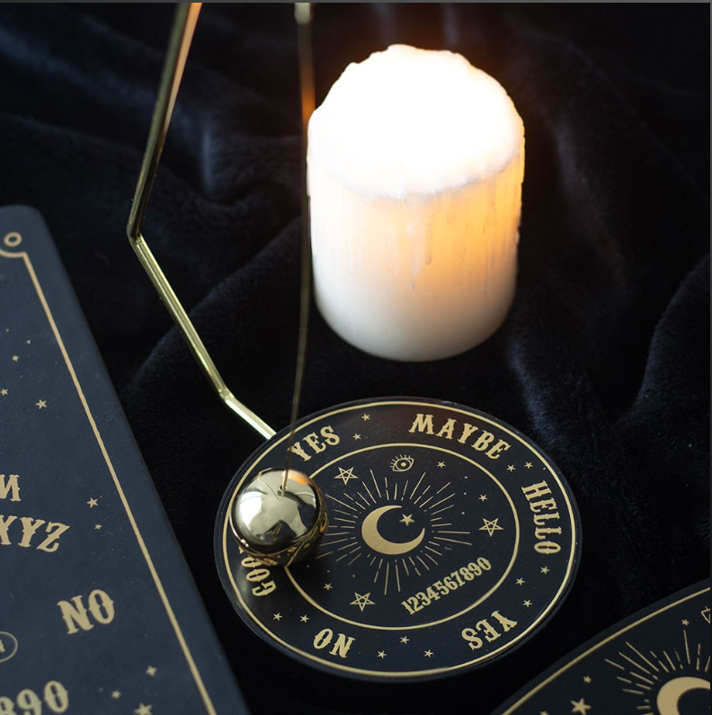 Talking board pendulum decision maker with triangular gold wire frame and silver ball pendulum on black matte celestial base